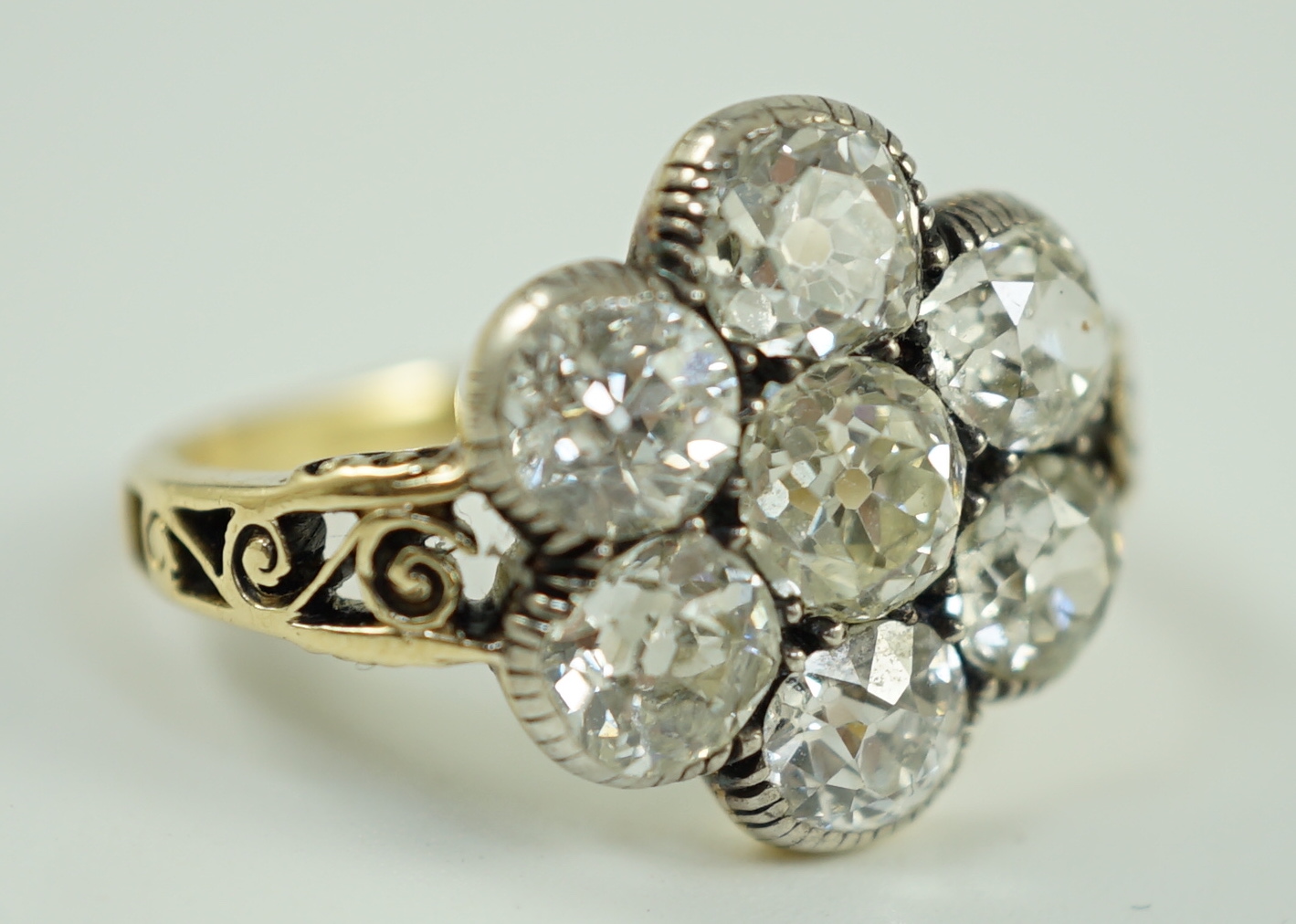 A late 19th/early 20th century gold and collet set seven stone old round cut diamond flower head cluster ring